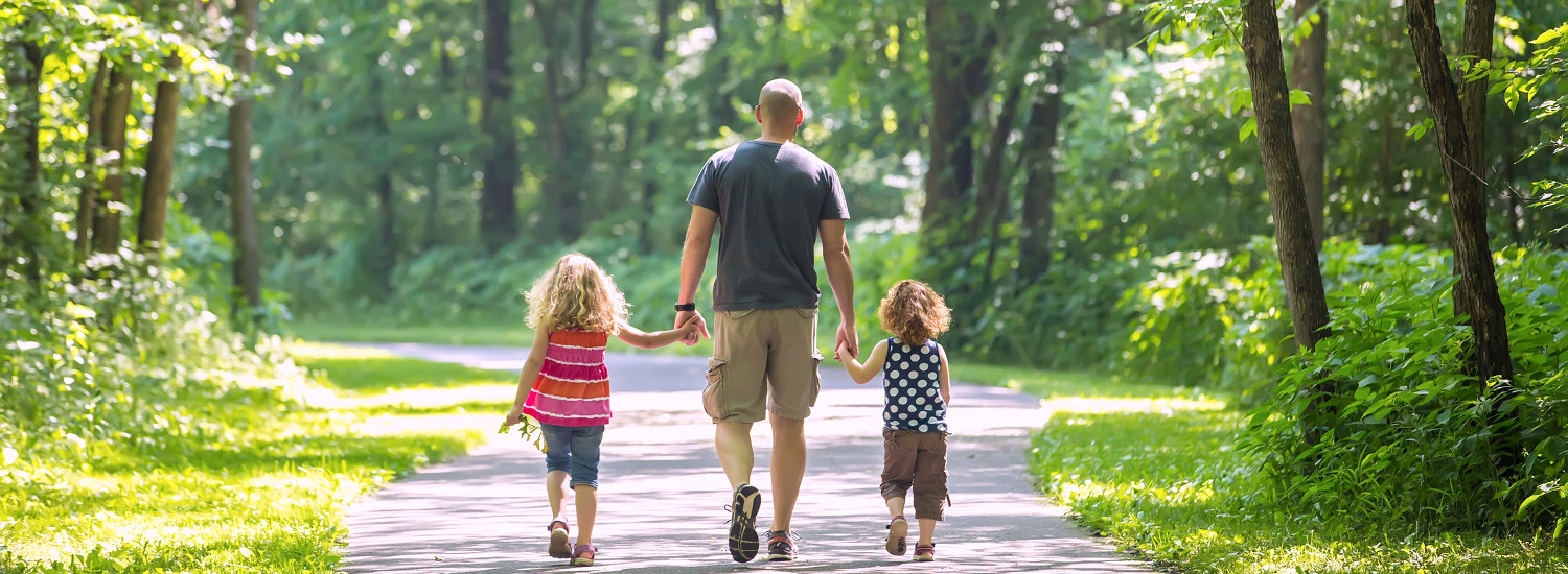 Photo of a father walking with two children.