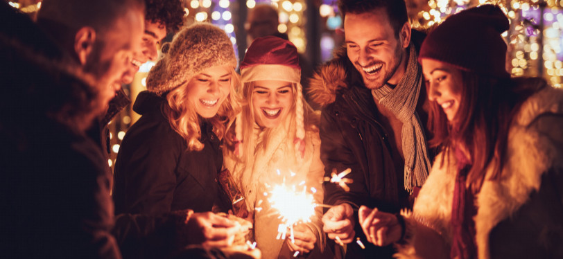 Six happy friends celebrating the holiday season with sparklers