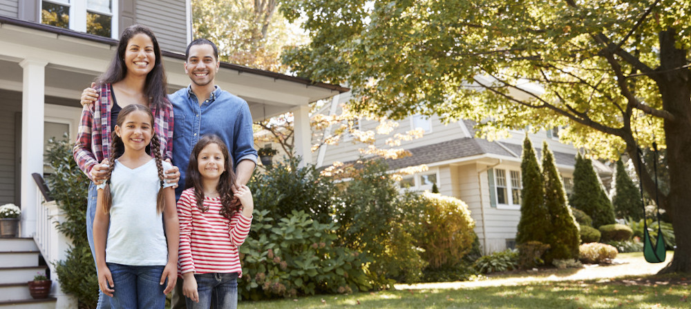 Photo of a young family in front of their home