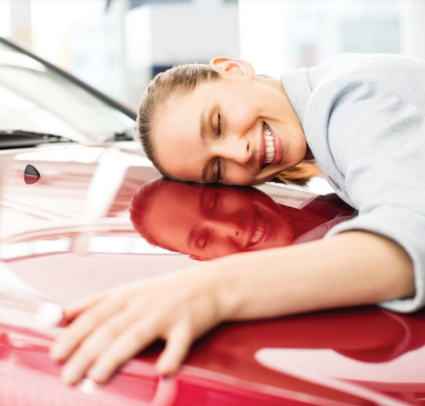 Photo of a woman hugging the hood of her shiny red car